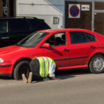 Photo of man changing the punctured tyre on the red car