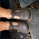 Legs and Shoes of a Little Baby in a Stroller