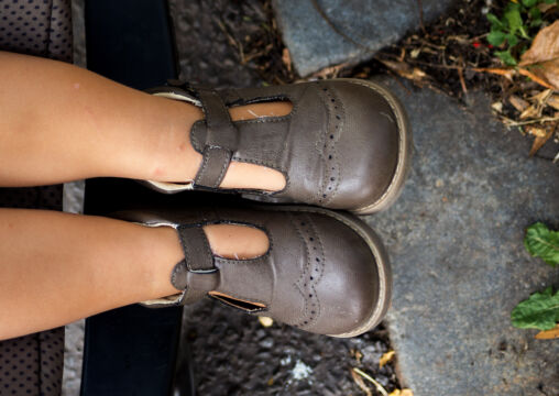 Legs and Shoes of a Little Baby in a Stroller