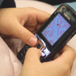 Young Girl Playing Sudoku On Old Mobile Phone