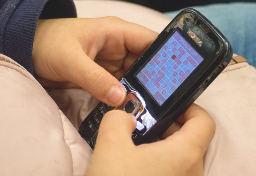 Young Girl Playing Sudoku On Old Mobile Phone