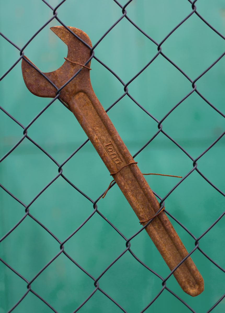 Free vertical image of rusty spanner on blue background