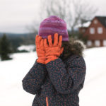 Little girl covers her face in winter
