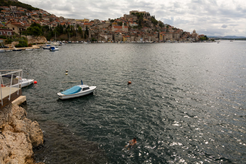 The view to Šibenik city with the sea shore and small boat in foreground.