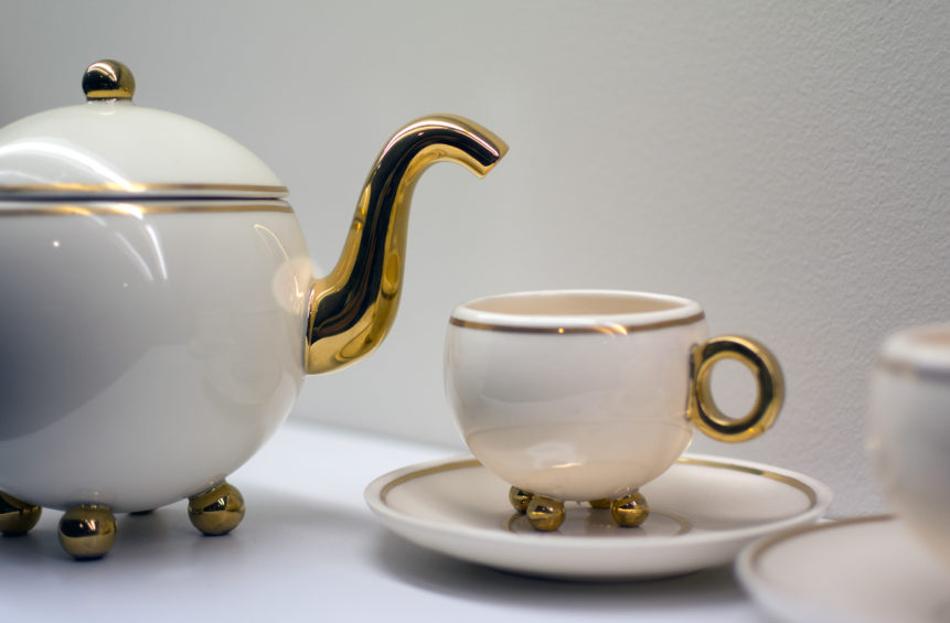 White teapot and cup of tea with golden decoration