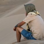 A lonely man sitting on a sand dune A lonely man sitting on a sand dune.