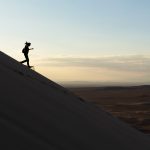 A woman runs down the sand dune