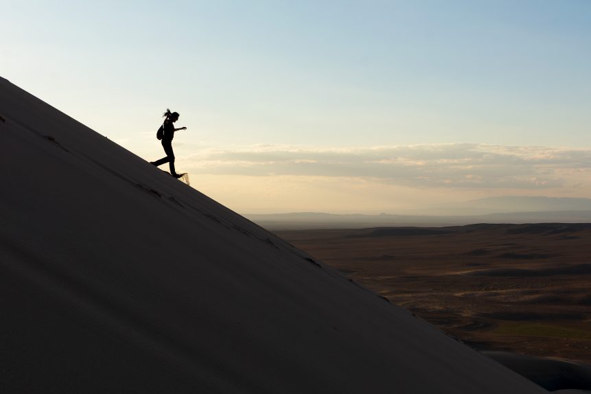 A woman runs down the sand dune