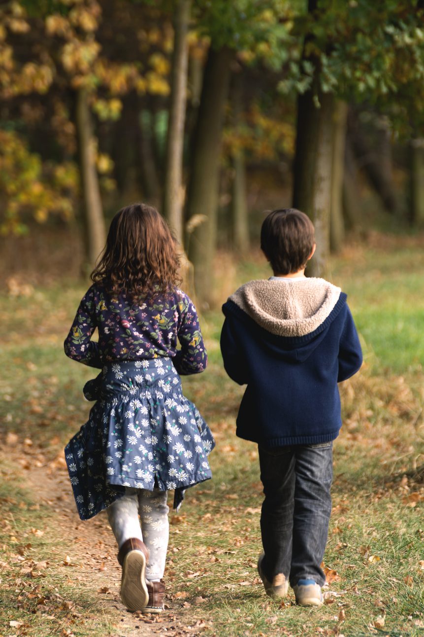 Boy and girl siblings walking in the woods