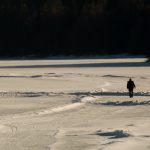 Lonely man walks away on frozen lake